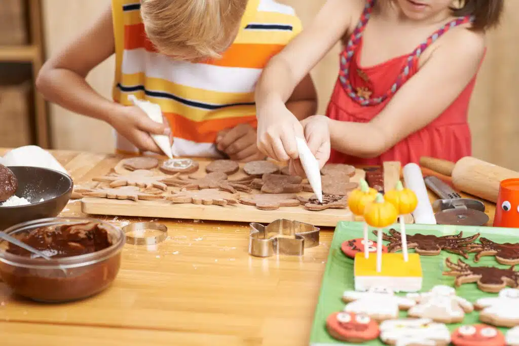 Siblings Decorating Cookies For Halloween Party